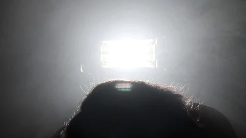 Person rolls head around in circle, with bright light behind bursting thru Stock Footage 121435729