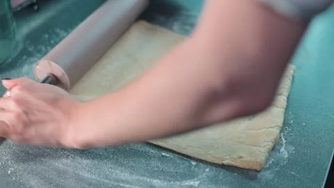 A person rolls out dough on a flat surface in a kitchen. The action shows hands Video stock 339095591