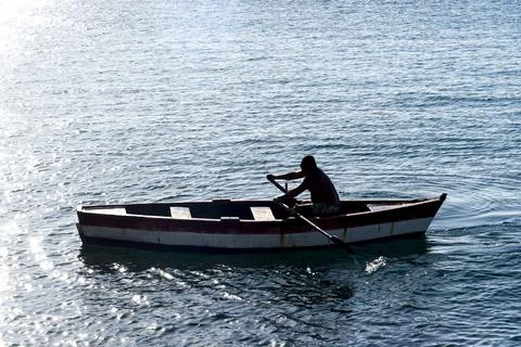 Person rowing a boat at sea. Stock Photos