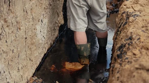 Person in rubber boots walking in muddy water Stock Footage 341294559