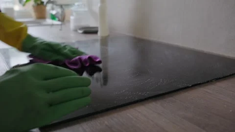 Person in Rubber Gloves Cleaning Induction Cooktop with Microfiber Cloth Stock Footage 345834607