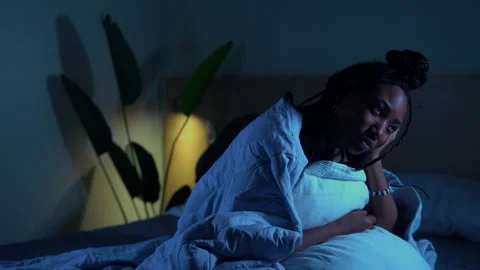 Person with sad expression sitting on bed at night Video stock 332300784