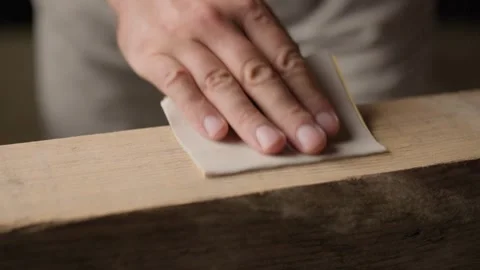 Person sanding raw timber plank with sandpaper Stock Footage 344601395