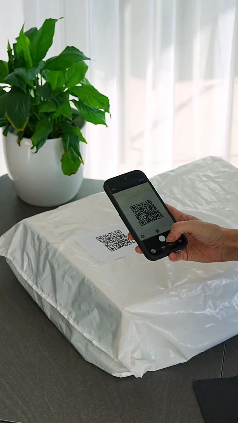 Person scanning QR code on parcel with smartphone camera for delivery tracking Stock Footage 345658730