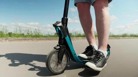 Person on a scooter on an empty road, changes his pushing leg and rolls forward Stock Footage 132793866