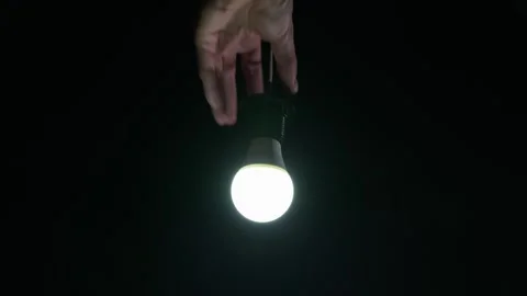 Person Screwing Flickering Led Light Bulb Into Hanging Socket in the Dark Stock Footage 334134661