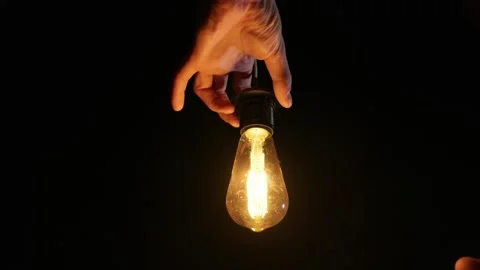 Person Screwing Flickering Light Bulb Into Socket in Deep Cinematic Darkness Stock Footage 333828641
