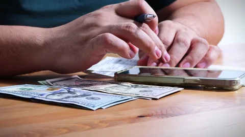 The person is scribbling notes next to a calculator and money Stock Footage 264983067