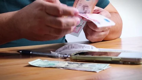 The person is scribbling notes next to a calculator and money Stock Footage 264983098