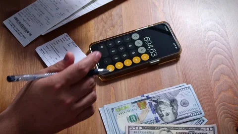 The person is scribbling notes next to a calculator and money Stock Footage 264983134