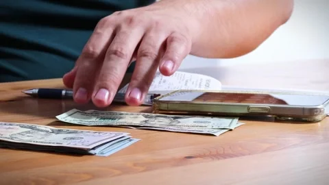 The person is scribbling notes next to a calculator and money Stock Footage 264983224