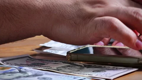 The person is scribbling notes next to a calculator and money Stock Footage 264983273