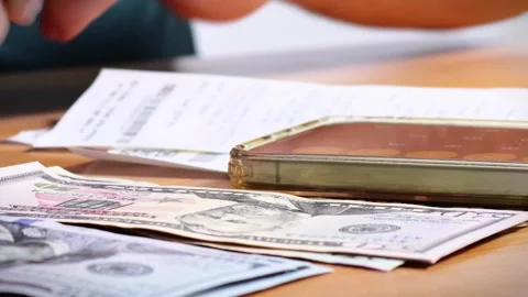 The person is scribbling notes next to a calculator and money Stock Footage 264983283