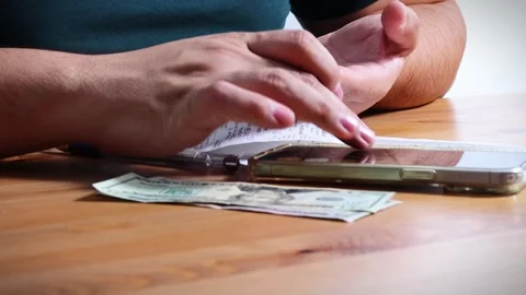 The person is scribbling notes next to a calculator and money Stock Footage 264983289