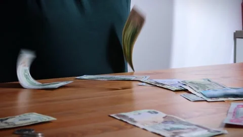 The person is scribbling notes next to a calculator and money Stock Footage 264983296