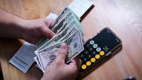 The person is scribbling notes next to a calculator and money Stock Footage 264983356
