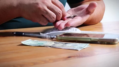 The person is scribbling notes next to a calculator and money Stock Footage 264983391