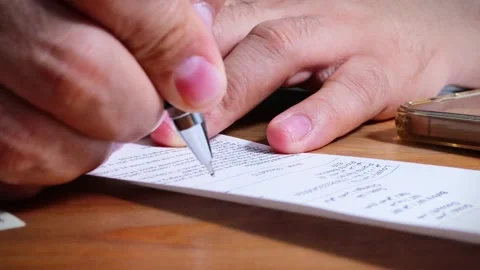 The person is scribbling notes next to a calculator and money Stock Footage 264983405