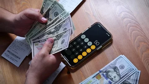 The person is scribbling notes next to a calculator and money Stock Footage 264983575