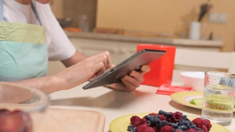 Person scrolling through a recipe on a tablet computer in a home kitchen Video stock 342762622