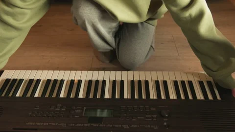 Person seated cross legged at keyboard with hands hovering above keys in warm 動画素材 343545807