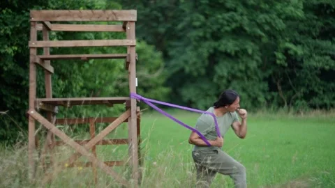 A person is seen exercising outdoors using resistance bands in a natural setting Stock Footage 279324685
