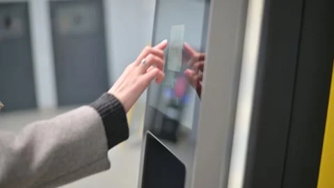 A person is seen using a touchscreen kiosk in an urban setting. The individual 库存影片 337555953