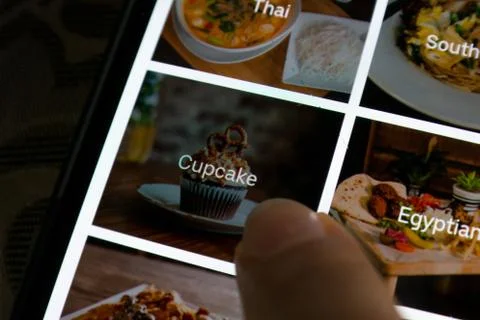 A person selecting cupcakes while ordering food online - Uber Eats delivery app Stock Photos
