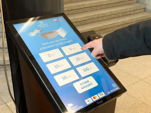 A person selecting a donation amount on an electronic chapel kiosk to support Stock Photos