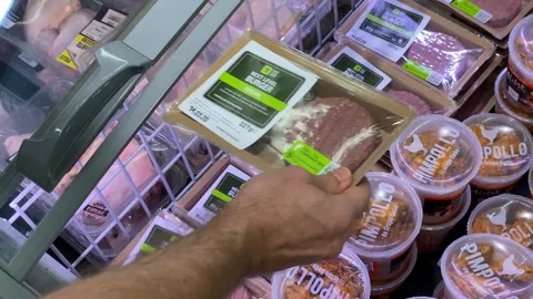 Person selecting packaged meat products in supermarket refrigerator section Stock Footage 336398488