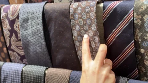 A person selecting a tie from a display of various neckties. 스톡 동영상 343300621