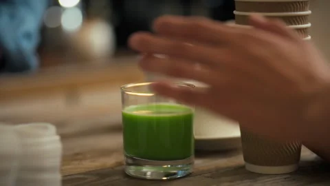 Person serving fresh green drink at a casual dining setting in a cozy cafe e Stock Footage 323870403