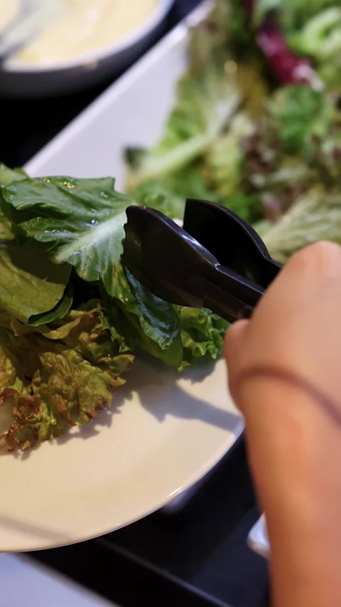 Person Serving Fresh Lettuce at Self-Serve Salad Bar Stock Footage 323339813