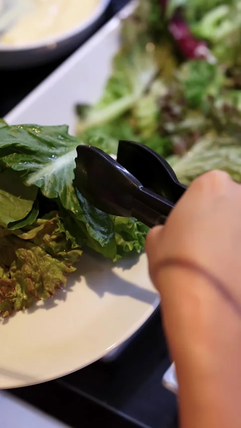 Person Serving Fresh Lettuce at Self-Serve Salad Bar Stock Footage 325826284