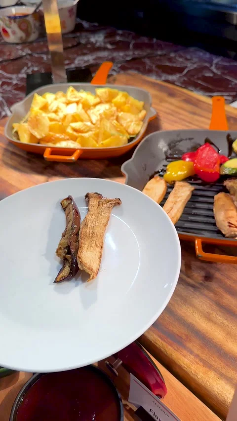 Person Serving Grilled Vegetables and Mushrooms onto Plate at Restaurant Buffet Stock Footage 335734179