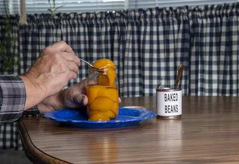 Person Serving Peaches From a Jar While Baked Beans Sit on Table in a Domes.. Stock Photos