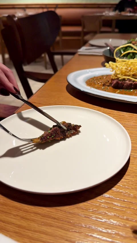 Person serving a piece of juicy beef steak onto a white plate Stock Footage 337462108