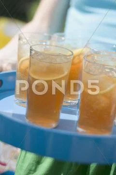Person serving several glasses of iced tea on a tray Stock Photos