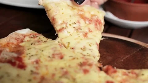 Person serving a slice of pizza on the table. People take slices of delicious Stock Footage 336586683
