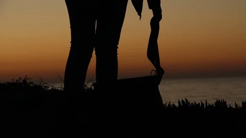 Person setting bags down by the ocean at sunset Stock Footage 123201858