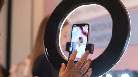 A person setting the phone on a ring-light for a record on makeup process Stock Footage 106664905