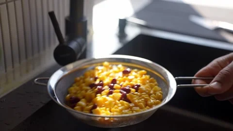 Person shakes strainer with corn and red beans over kitchen sink Stock-Footage 345754393