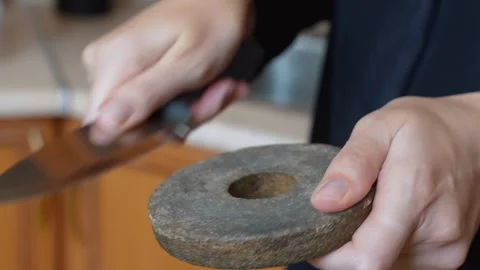 Person sharpening kitchen knife on an old grindstone Stock Footage 327670262