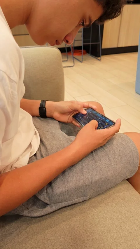 A person is sitting on a couch and playing a game on their cell phone Stock Footage 328775113