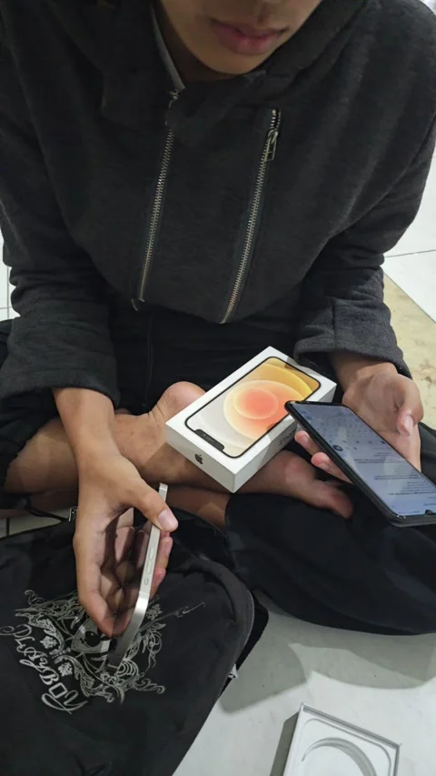 Person Sitting Cross-Legged Checking New White Smartphone And Box Stock Footage 340079607