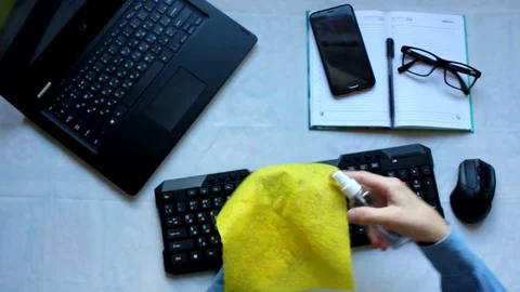 A person sitting on the keyboard of a laptop computer wipes the keyboard and Stock Footage 129462846