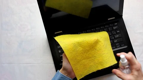 A person sitting on the keyboard of a laptop computer wipes the keyboard with an Stock Footage 129462943