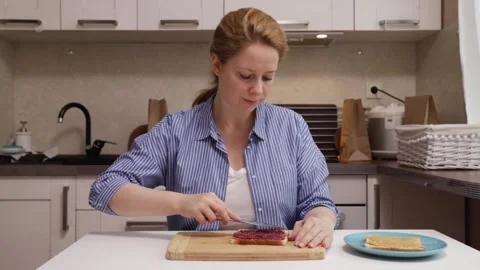 A person sitting at the kitchen table, savoring a peanut butter sandwich,wo.. Stock Footage 252019817