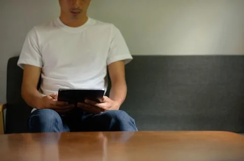 Person Sitting on Sofa Using Tablet Device in Indoor Setting Stock Photos
