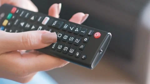 A Person Sitting on sofa while flipping through TV channels with remote con.. Stock Footage 257875057